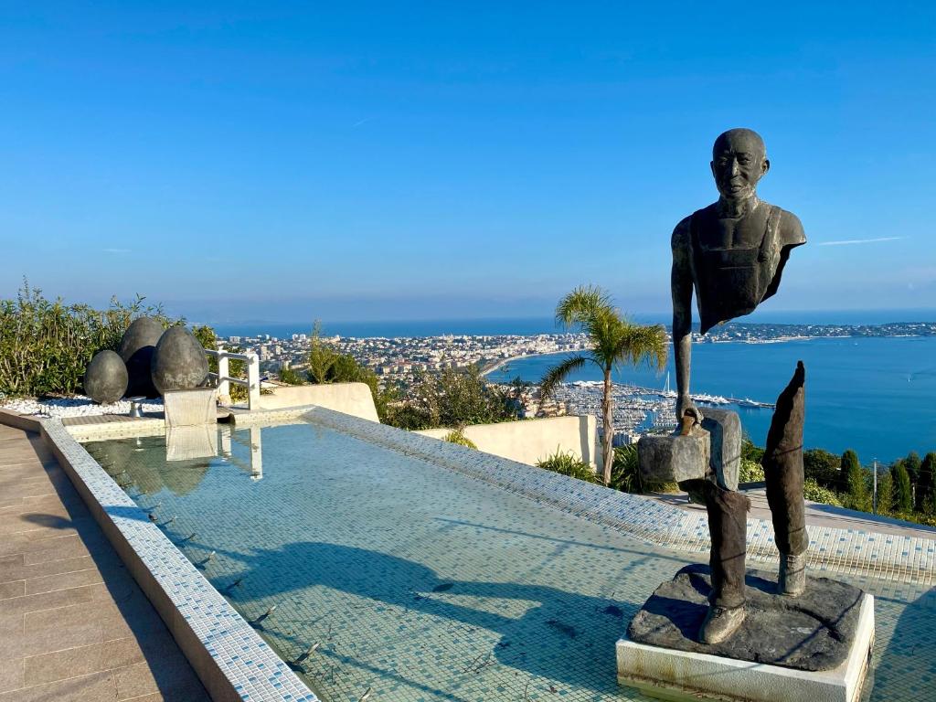 une statue d'un homme debout à côté d'une piscine dans l'établissement Bas de Villa VUE PANORAMIQUE, à Vallauris