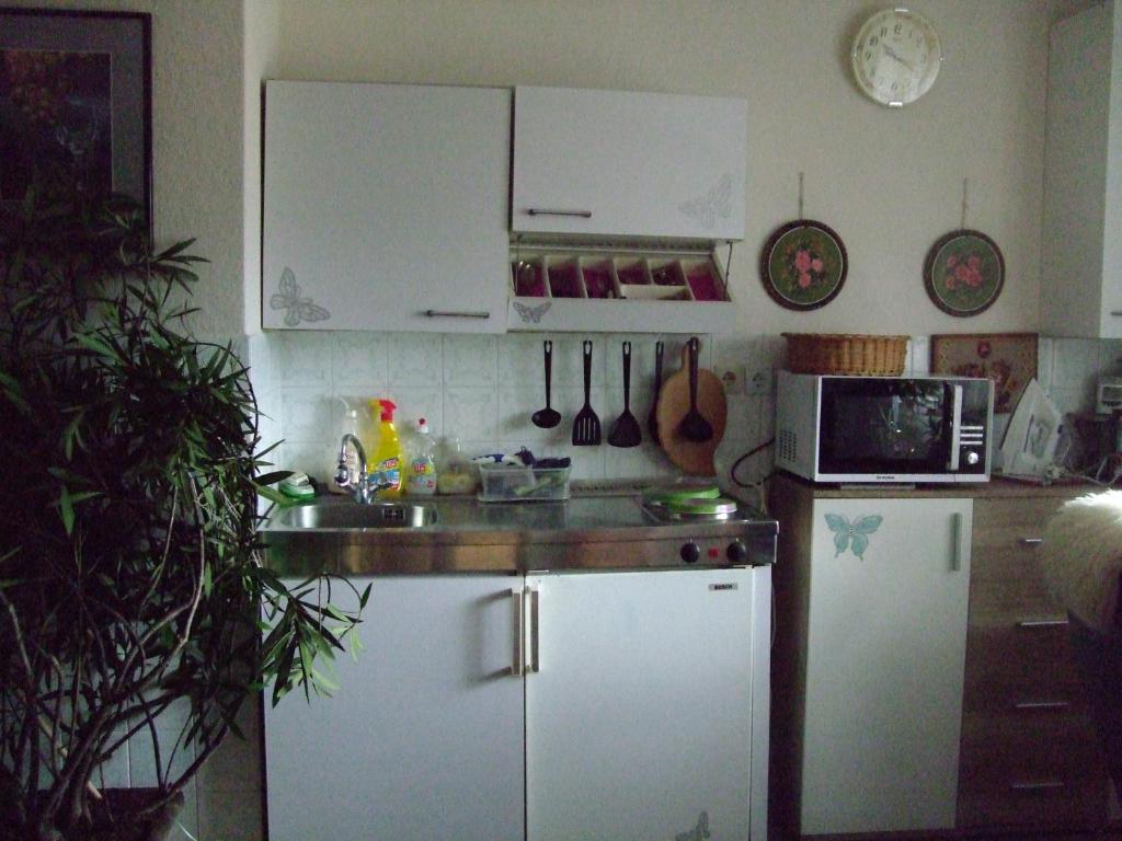 a kitchen with white cabinets and a sink and a microwave at Pension Krüger in Seeboden