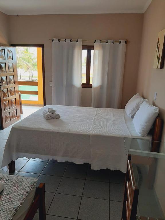 a bedroom with a large white bed with white curtains at Pousada Costa do Sol in Canavieiras