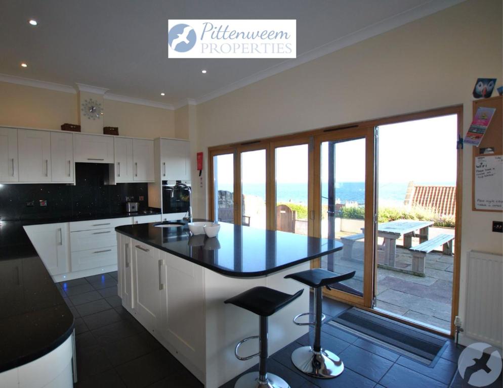 Una cocina con una encimera con taburetes. en Anchor House Pittenweem - Seaview home, en Pittenweem