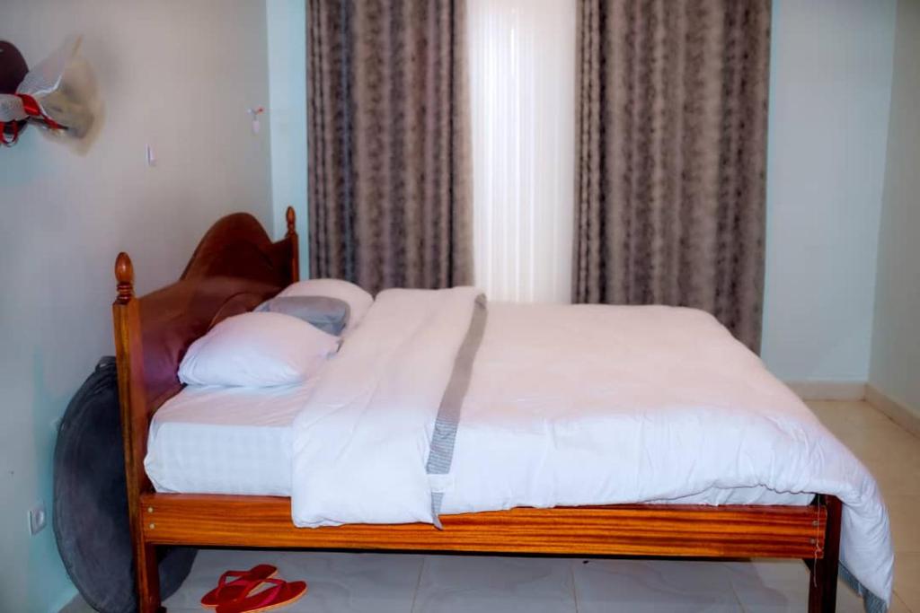 a bed with white sheets and pillows in a bedroom at RUBIRIZI Residence in Kigali