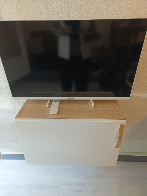 Une télévision à écran plat est installée au-dessus d'un tiroir blanc. dans l'établissement Studio La Favière Bormes les Mimosas, à Bormes-les-Mimosas