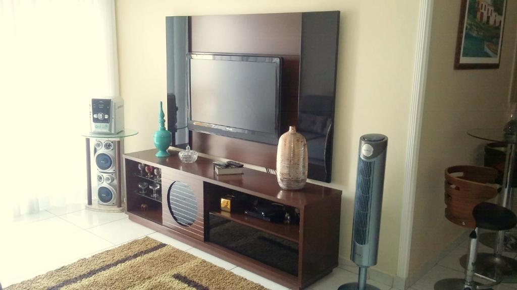 a living room with a flat screen tv on a entertainment center at Quarto aconchegante Jatiúca in Maceió