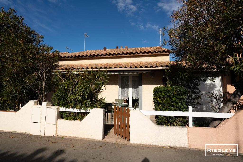 une maison avec une clôture blanche et un portail dans l'établissement Maison de vacances à 600m de la plage, à Vias