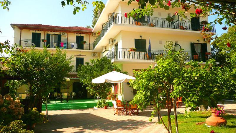 a large building with an umbrella and tables and chairs at Des Roses Hotel in Platanias
