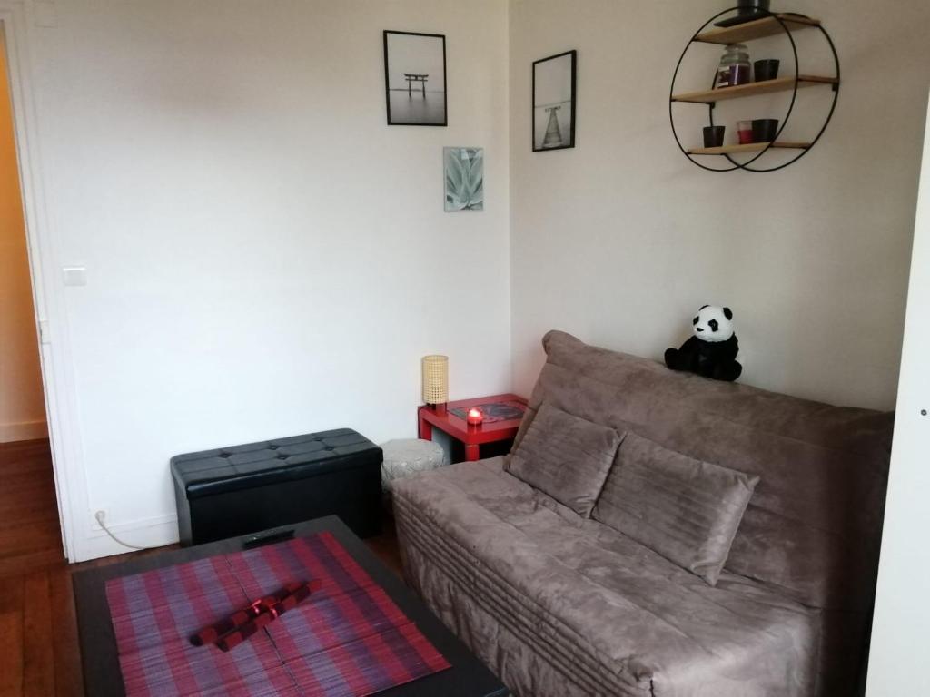 - un salon avec un canapé et un ours panda sur le mur dans l'établissement Chez Sophie, cosy et calme, à deux pas de Paris, à Saint-Mandé