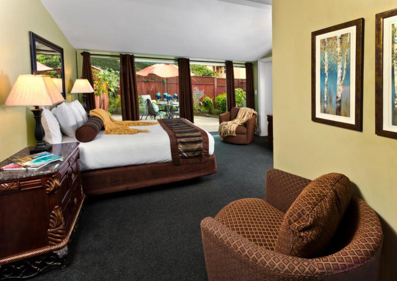 a bedroom with a bed and a desk and chairs at Monterey Peninsula Inn in Pacific Grove