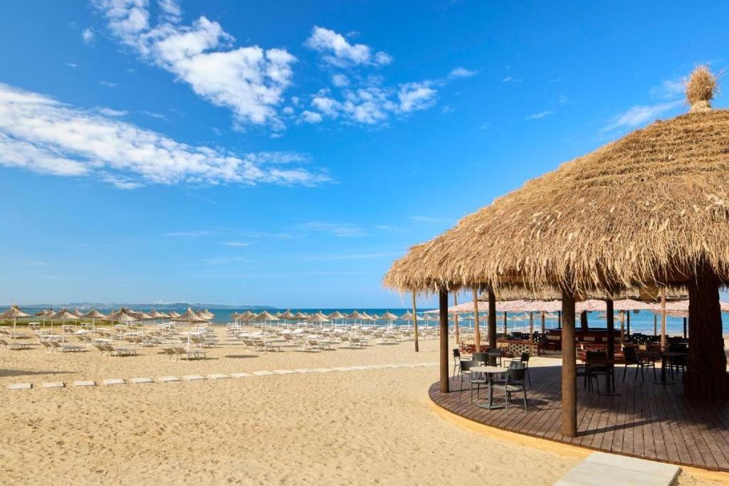 a beach with a straw umbrella and chairs and the ocean at Villa Prive Zone in Lalzit Bay