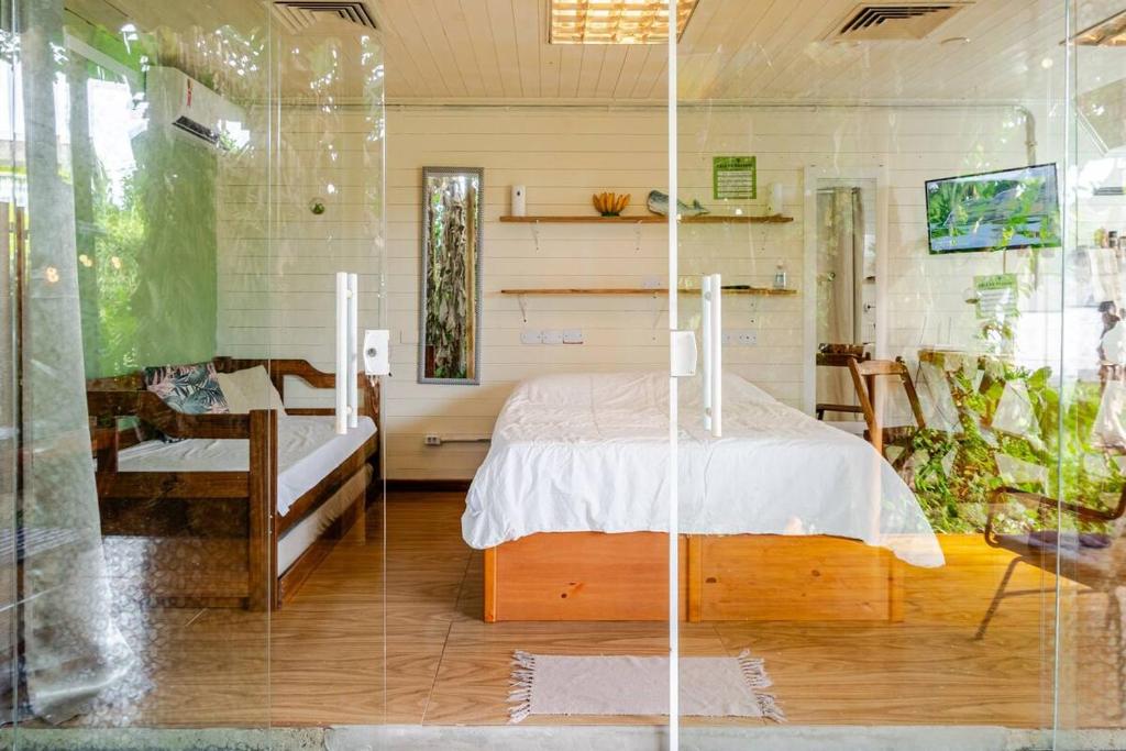 a bedroom with a bed and a glass wall at Casa do bananal - Praia Estaleiro (Ubatumirim) -Ubatuba/SP in Ubatuba