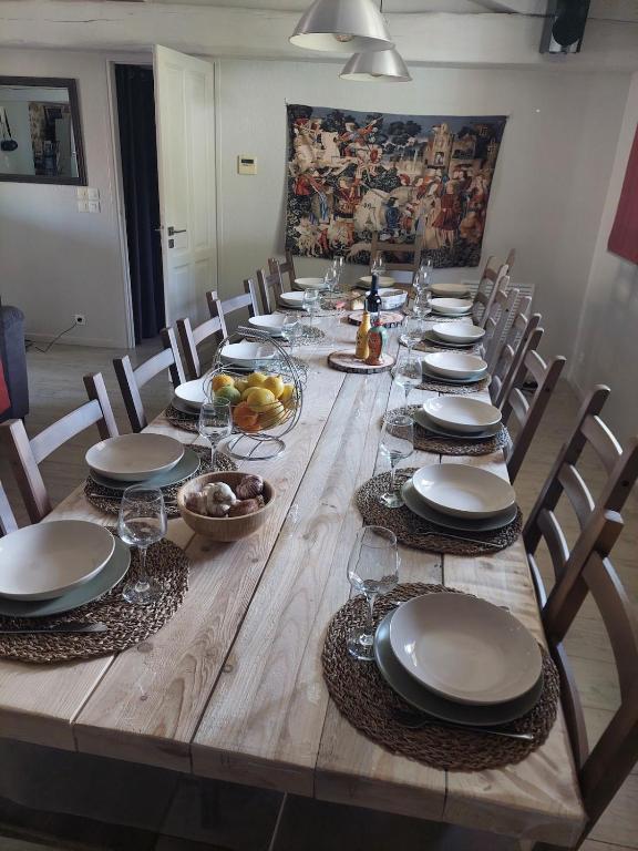 une grande table en bois avec des chaises et des assiettes. dans l'établissement Horizon des Corbières, à Saint-André-de-Roquelongue