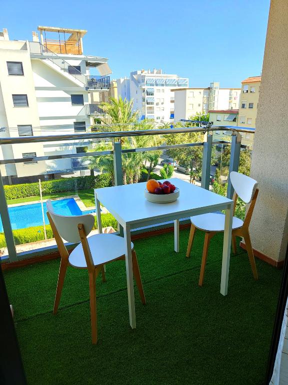a white table and chairs on a balcony with a bowl of fruit at Enjoy the beach in Bellreguart
