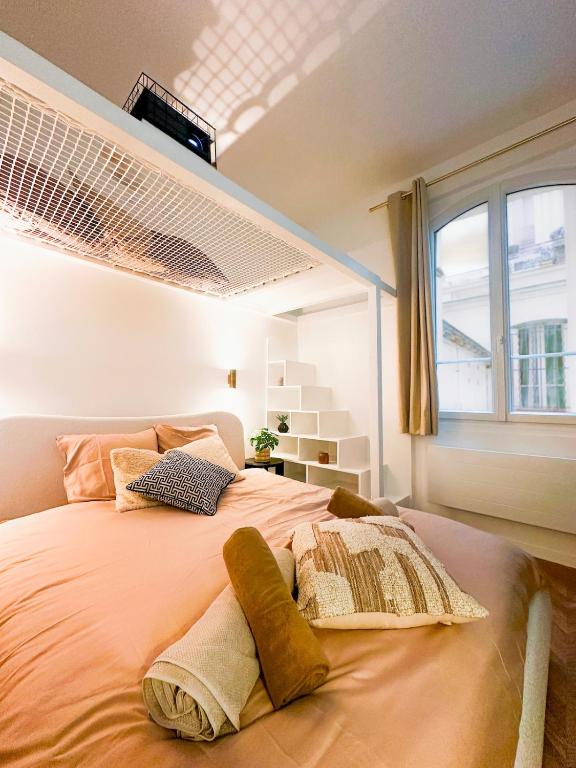une chambre avec un grand lit avec des oreillers dessus dans l'établissement Balnéo & cinéma suspendu - Paris 14ème, à Paris
