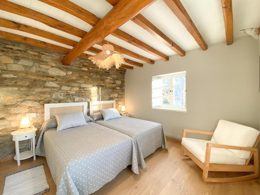a bedroom with a bed and a stone wall at Casa Pastur in Serantes