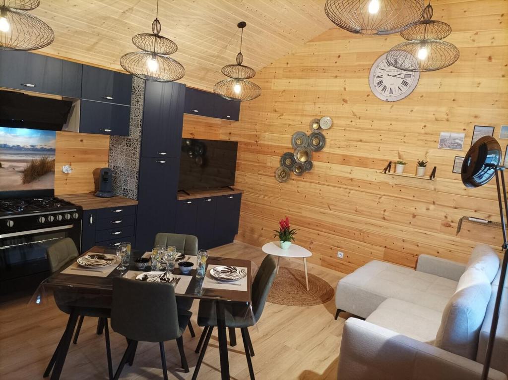 eine Küche und ein Wohnzimmer mit einem Tisch und einer Uhr in der Unterkunft Cottage "Au ptit bonheur" in Bourbourg