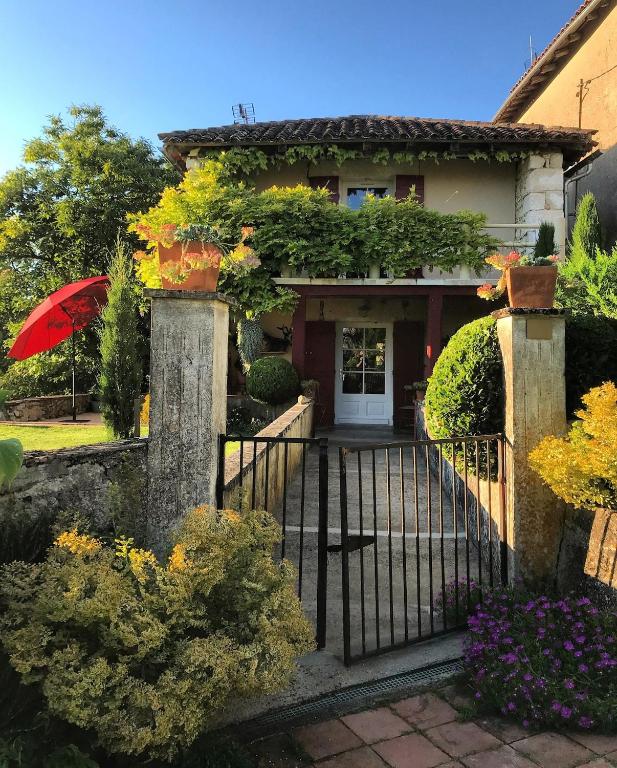 une maison avec un portail et un parapluie rouge dans l'établissement Le Parasol Rouge, à Saint-Sylvestre-sur-Lot