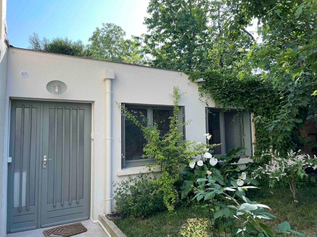 une petite maison blanche avec deux portes de garage dans l'établissement Studio 40m2 Antony, à Antony