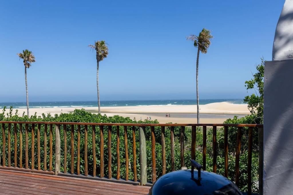 a view of a beach with palm trees and a fence at A Stone's Throw from the Ocean in Seafield