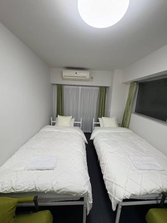 Hotel xinsuyuyuan 601, a room with two beds and a tv in it at xinsuyuyuan 601 in Tokyo