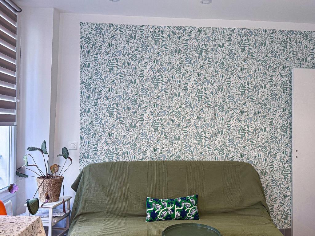 - un salon avec un canapé vert en face d'un mur dans l'établissement Le pot de fer Paris 5, à Paris