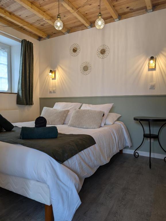 une chambre avec un grand lit et une table dans l'établissement Gîte Les Hortensias Les Jardins de Kerellec 20min de la mer jacuzzi et terrasse, à Plouvorn