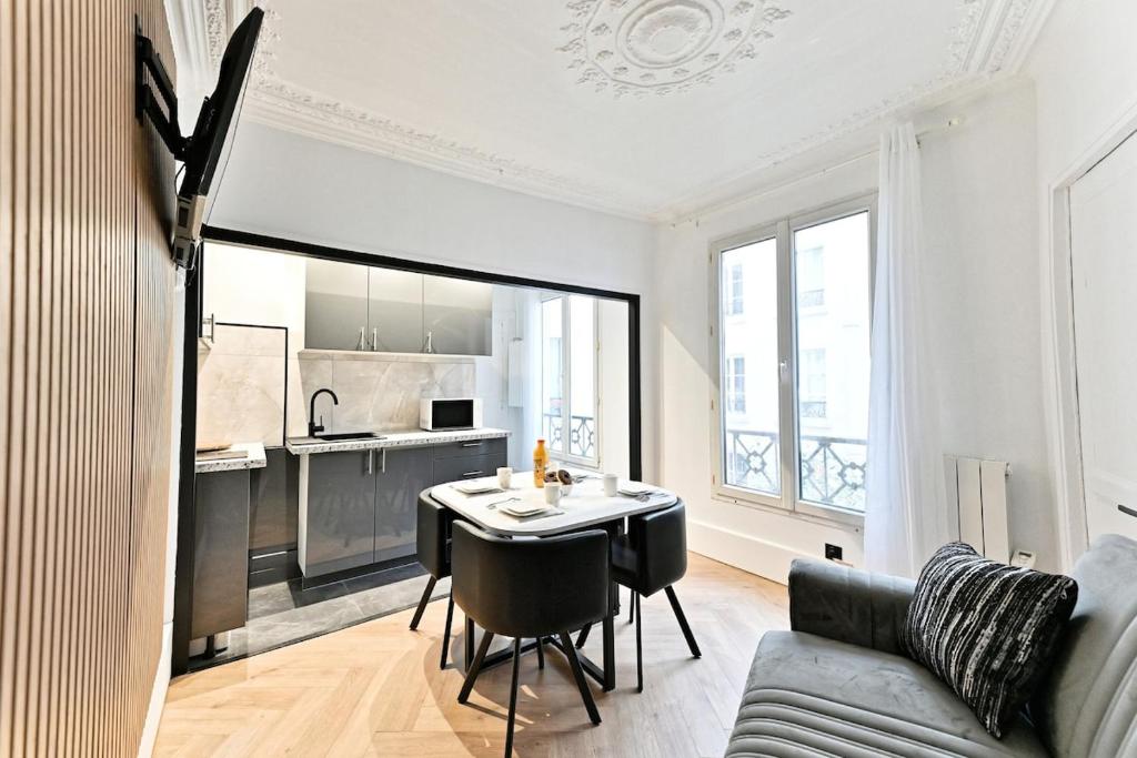 une cuisine et un salon avec une table et un canapé dans l'établissement Modern apartment Paris Moulin Rouge, à Paris