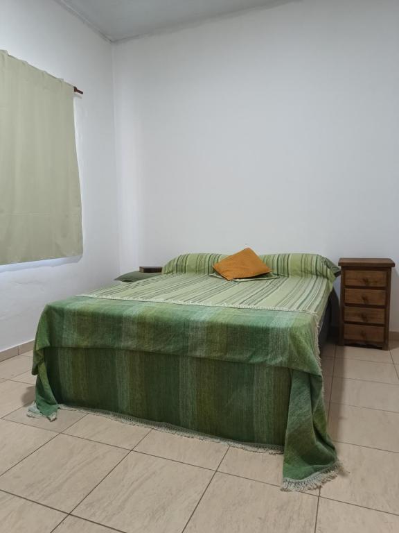 ein Bett in einem Zimmer mit einer grünen Decke darauf in der Unterkunft Campos del Paraná Casa Quinta in San Pedro