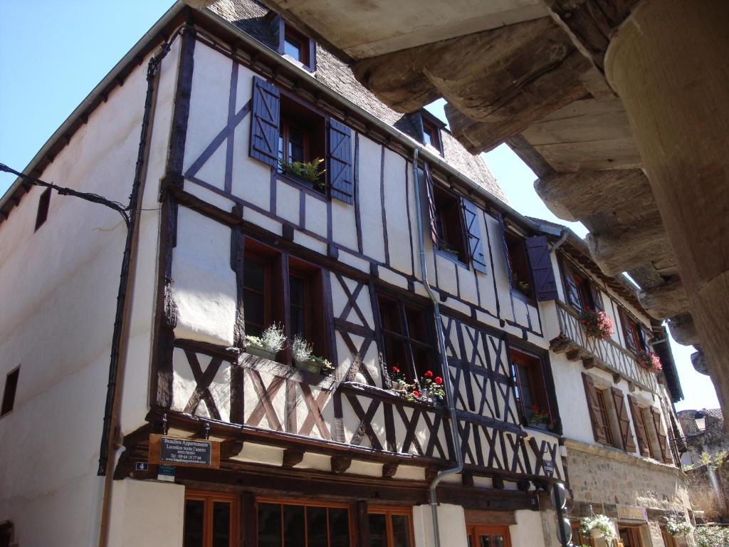 un vieux bâtiment avec des plantes en pot sur les fenêtres dans l'établissement Beaulieu Apartments, à Beaulieu-sur-Dordogne