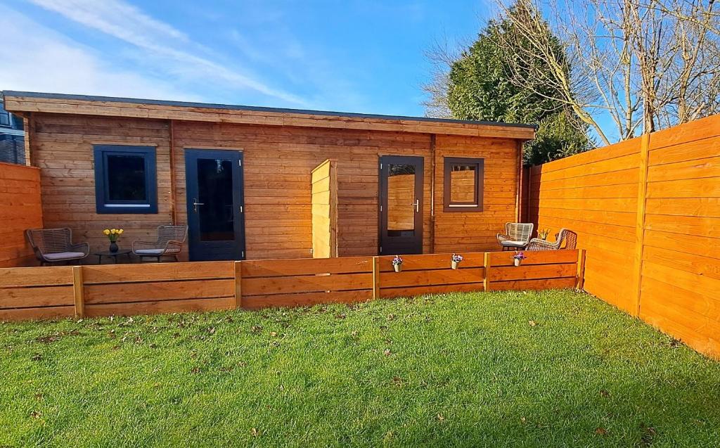 a wooden cabin with a fence in the grass at Guesthouse Purmerend near Amsterdam Volendam in Purmerend