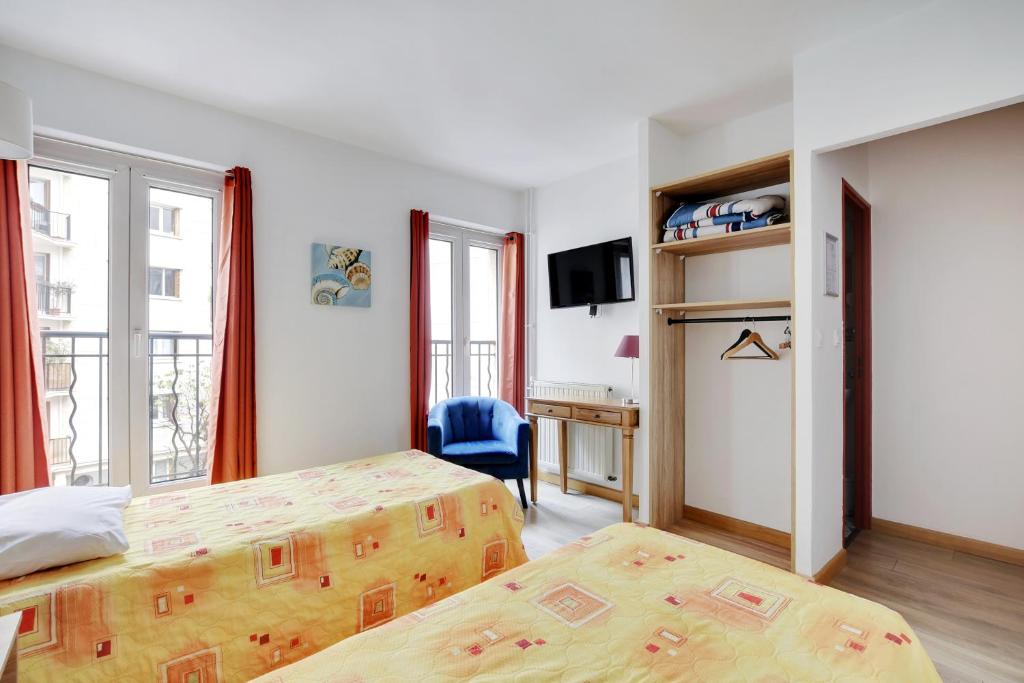 a bedroom with two beds and a desk and a tv at Hotel de l'Europe in Paris