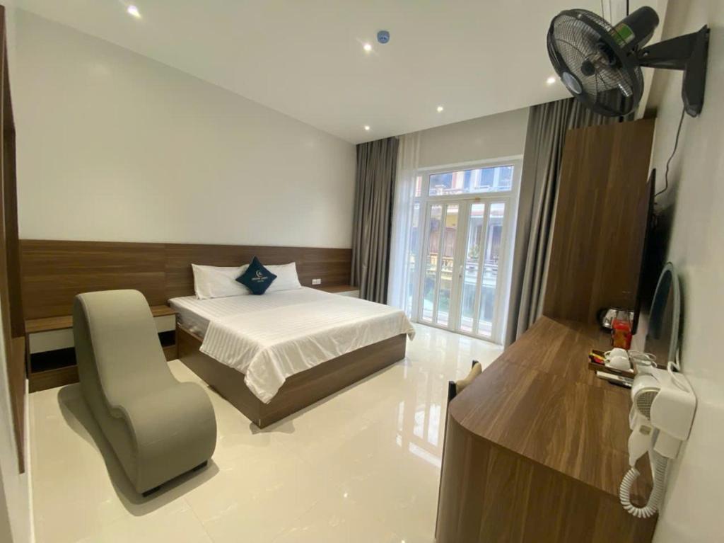 a bedroom with a bed and a chair and a fan at Nhà Nghỉ Moonlight in Hanoi