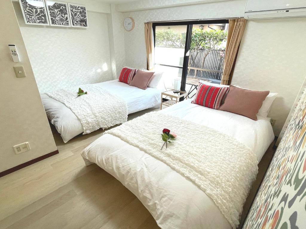 a room with two beds with flowers on them at #3 新宿まで2分! 清潔で安全な部屋! WiFi無料! in Tokyo