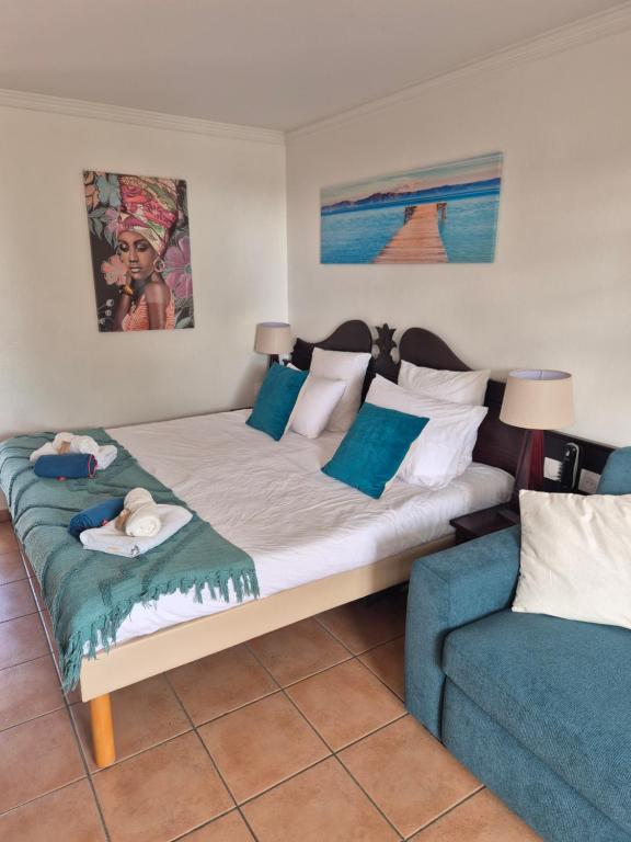 a bedroom with a large bed and a couch at Studio Ti Gwama Village Vacances in Sainte-Anne