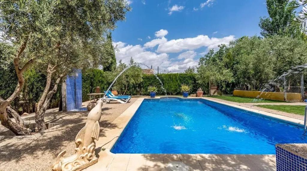 a swimming pool in a yard with a person sitting in a chair next to it at Spacious villa with mountain view and pool in Baza in Baza
