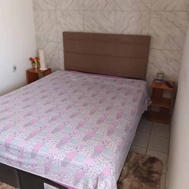 a bedroom with a bed with a pink comforter at Pousada Maria Guapa in São Gabriel