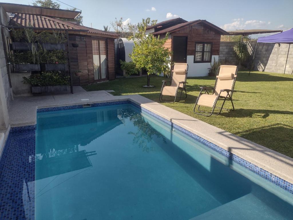 una piscina in un cortile con sedie e una casa di Aldea Xochi cabañas a Chiconcuac