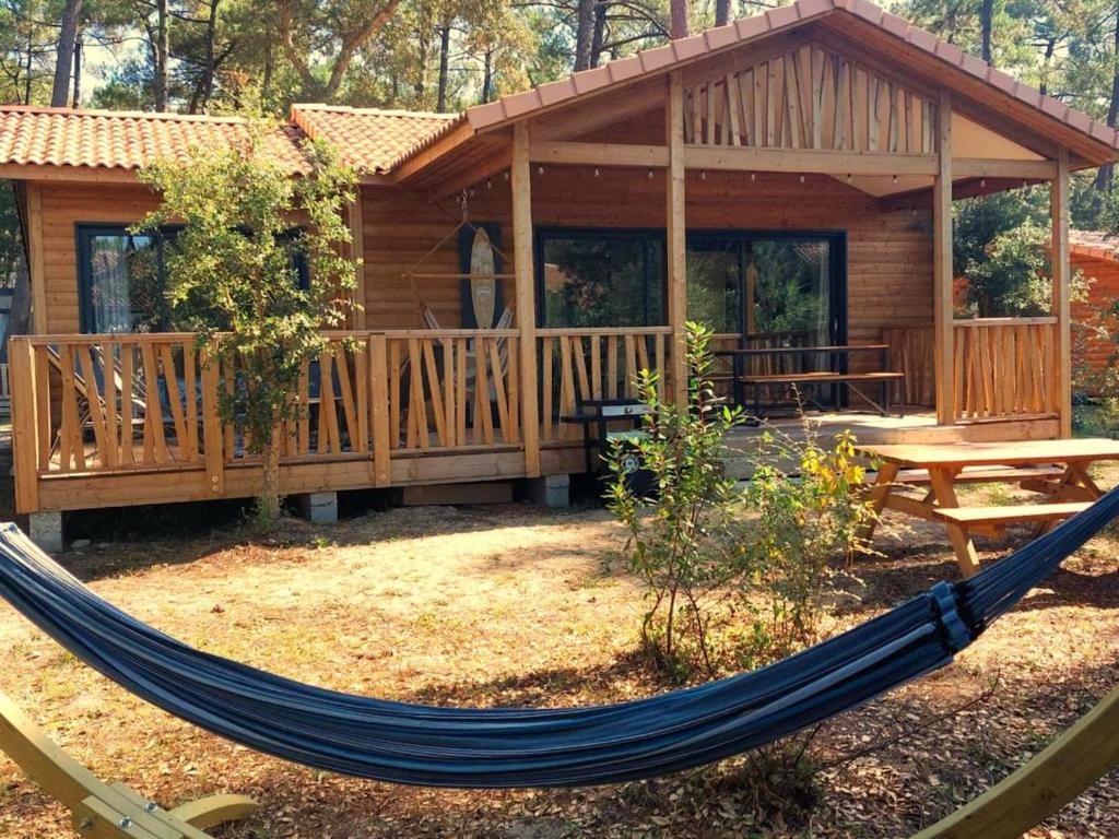 - un hamac en face d'une cabane en rondins dans l'établissement Green Resort Chalet with Clim & Pool, à Ondres