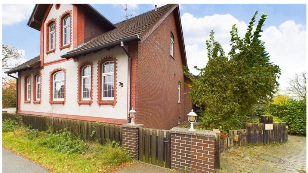 a red brick house with a fence in front of it at Charmante Ferienwohnung in Garbsen Stilvoll Geräumig in Garbsen