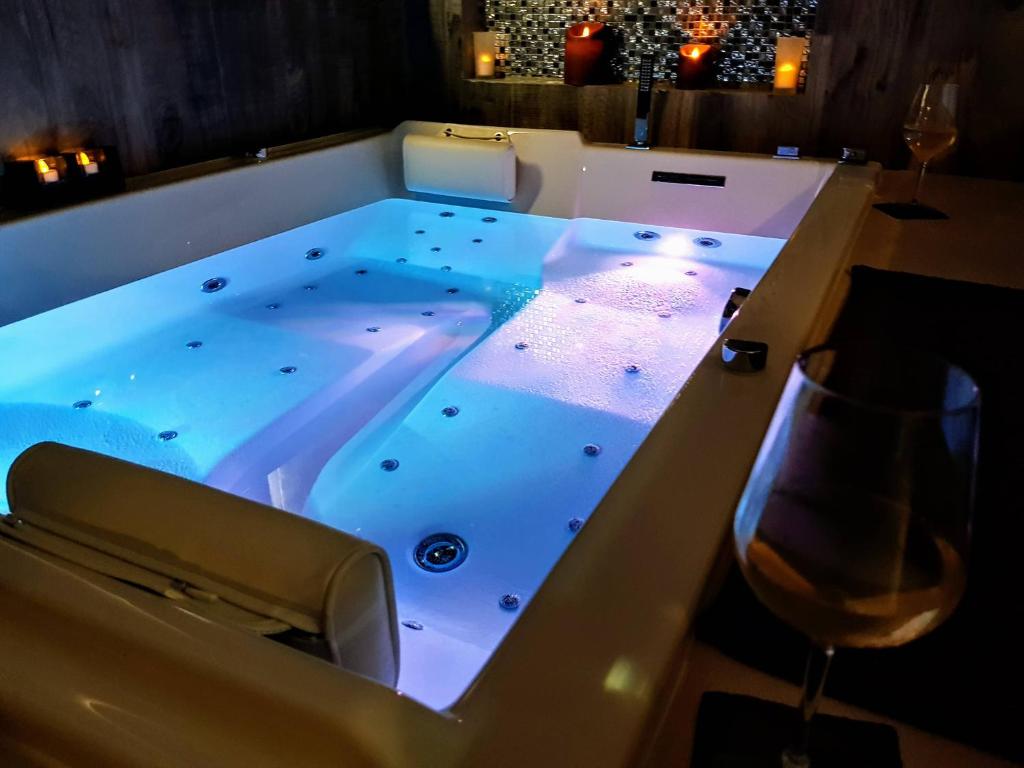 a jacuzzi tub in a room with a wine glass at La Petite Escapade, maison avec jacuzzi privatif in Héricy