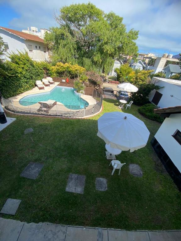 a pool with an umbrella and chairs and a table at Hotel Capri in Villa Gesell