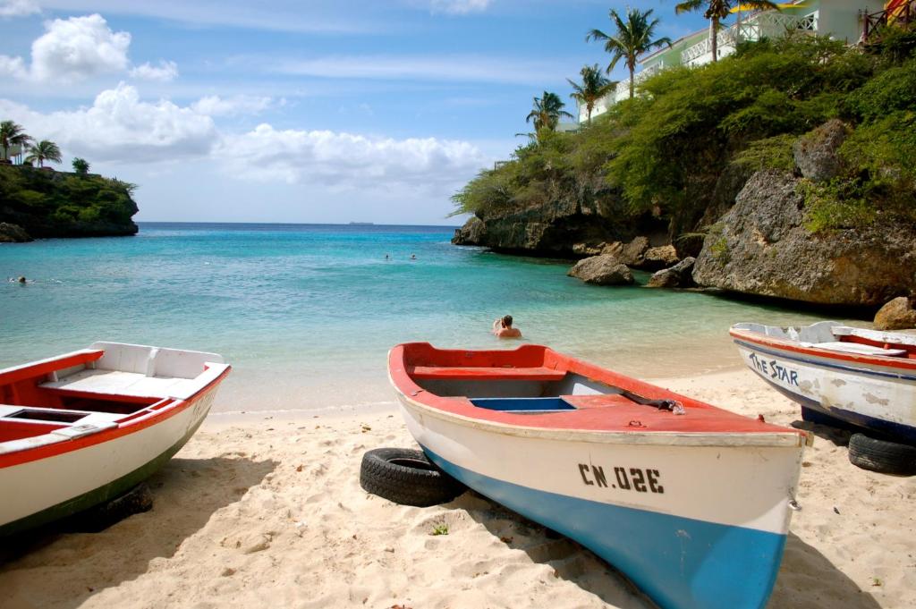 two boats sitting on the sand on a beach at Bon Bini Lagun Curacao in Lagun