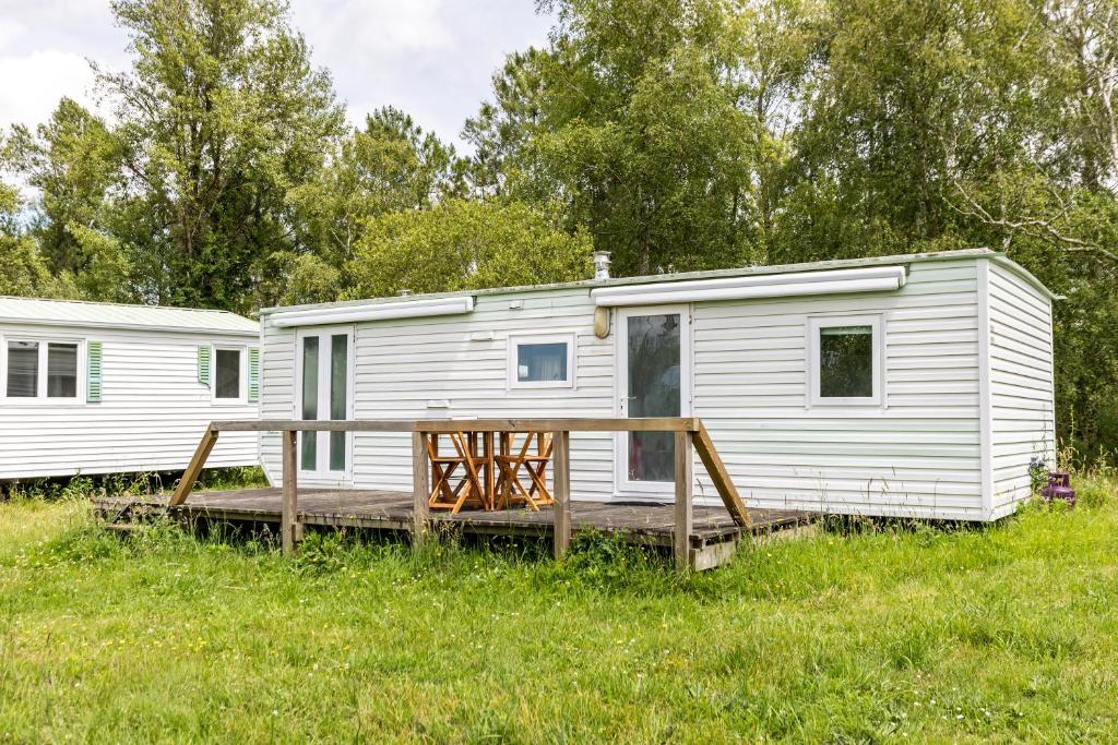 une remorque blanche avec terrasse couverte dans un champ dans l'établissement L'héberge du lac d'Isachris mh3, à Queyrac