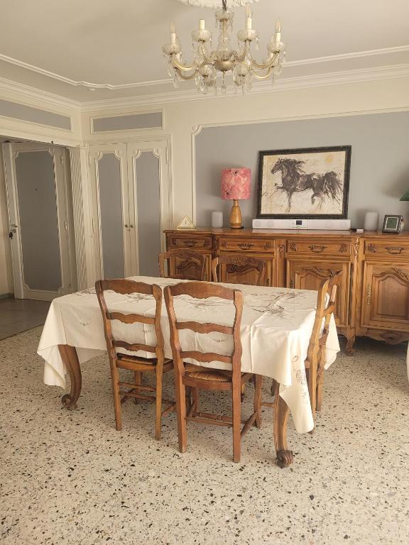 une table à manger avec quatre chaises et un lustre dans l'établissement Confortable appartement 2 chambres au centre d'Alès, à Alès