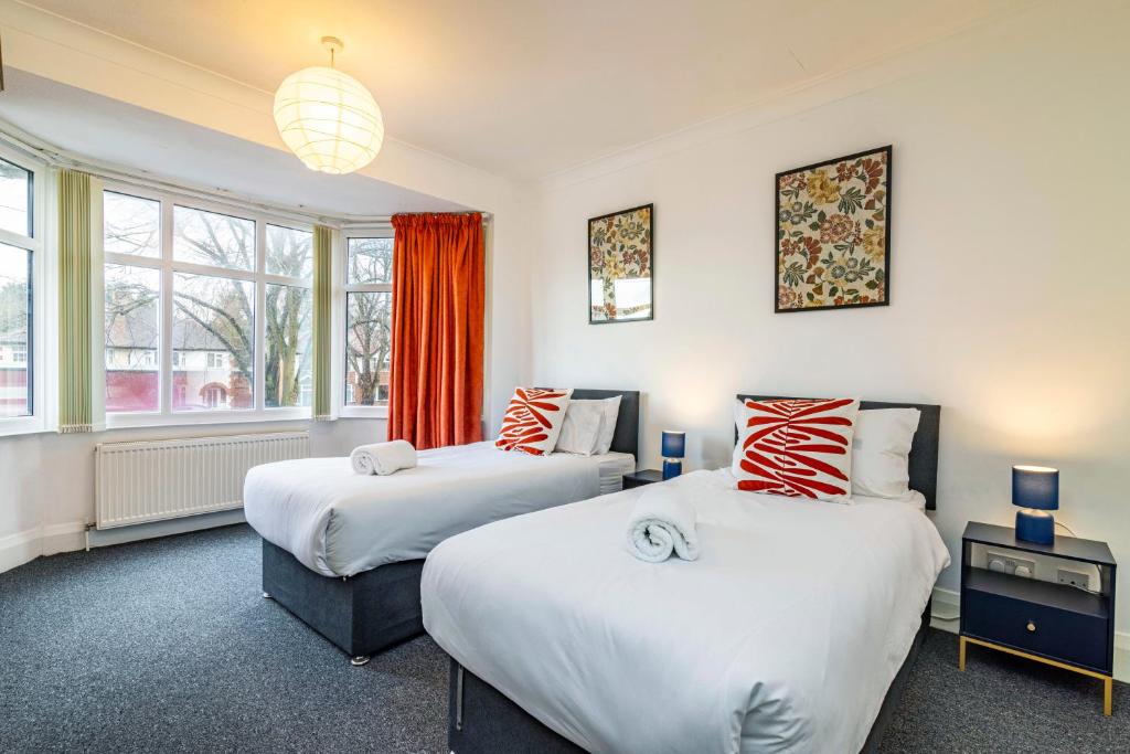 two beds in a room with two windows at University View-Off-Street Parking-Sleeps 8-Fast WiFi in Nottingham