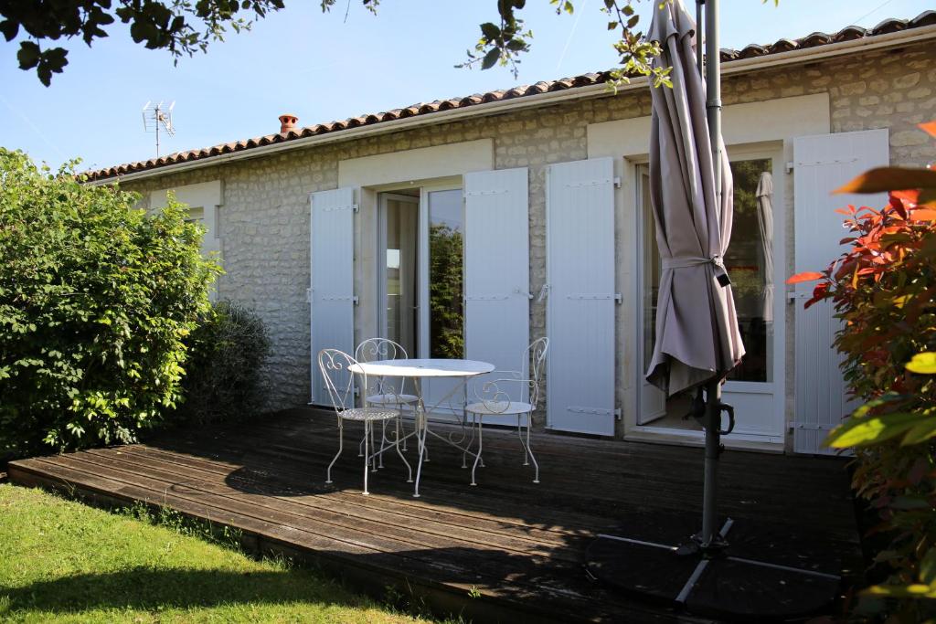 - une table et des chaises sur une terrasse en bois avec un parasol dans l'établissement Gite le Maine des Rois, à Juillac-le-Coq