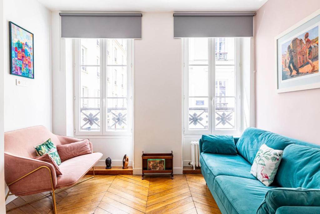 - un salon avec un canapé bleu et 2 fenêtres dans l'établissement GuestReady - A lovely stay in Batignolles, à Paris