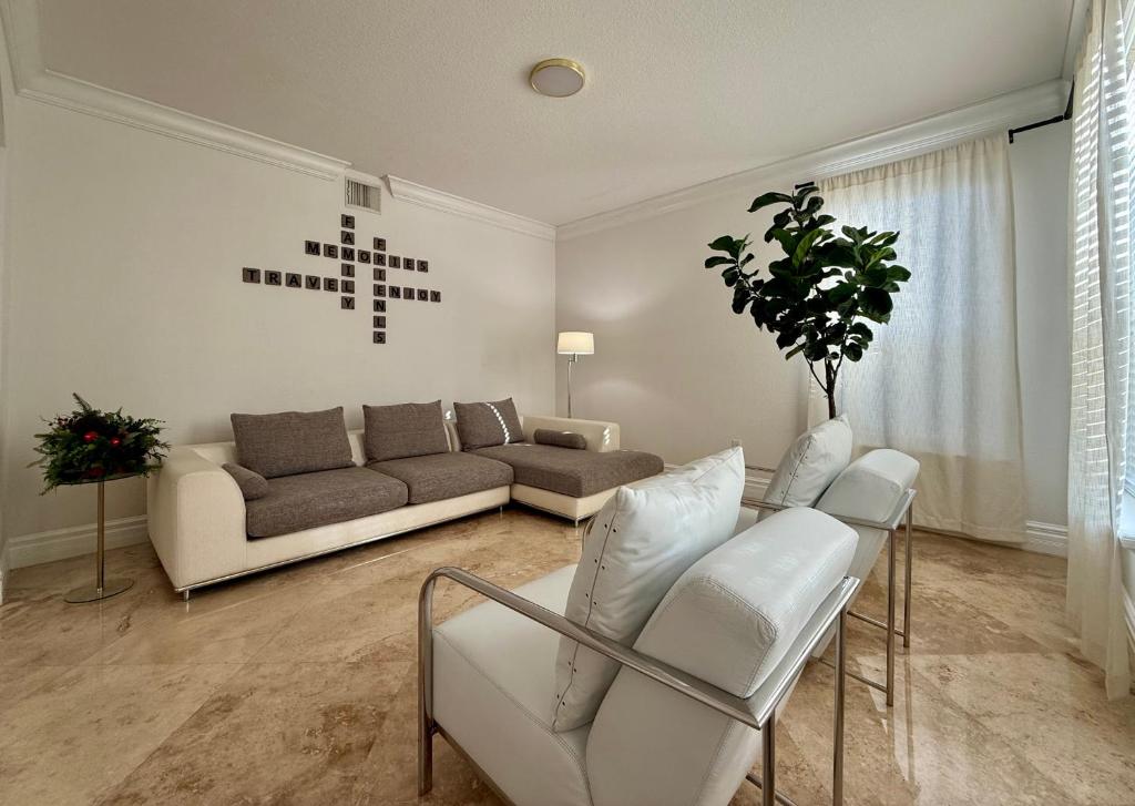 ein Wohnzimmer mit einem Sofa und weißen Stühlen in der Unterkunft Miami Getaway Heated Pool Villa with Mini Golf &amp; BBQ in Miami