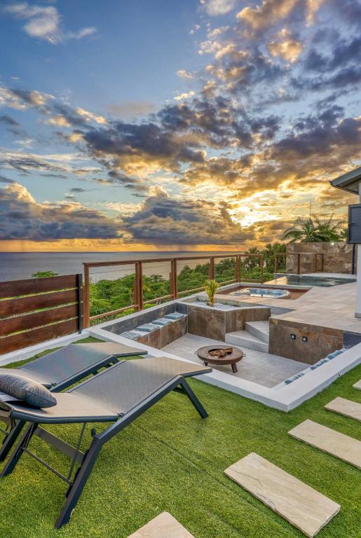 a patio with a table and chairs on the grass at Villa Panorama Grand Anse in Petite Île
