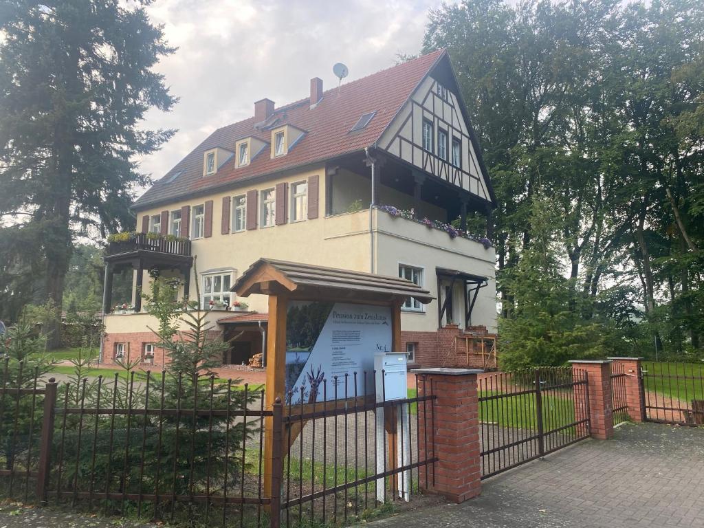 a large house behind a fence with a gate at Pension zum Zenshaus kleine Auszeit in Lychen