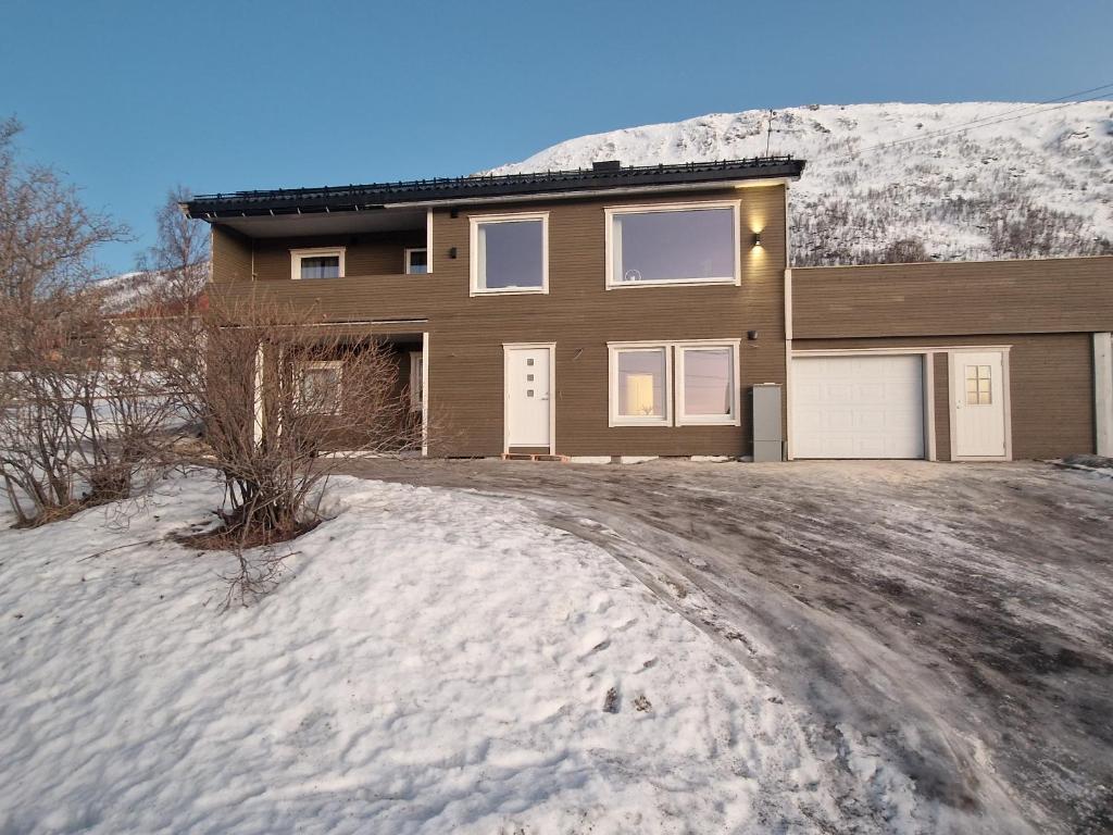 a house with a snow covered mountain in the background at apartment With fantastic view and parking in Tromsø