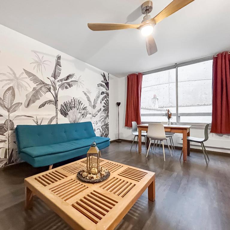 un salon avec un canapé bleu et une table dans l'établissement Charmant Duplex Hyper Centre Nancy, à Nancy